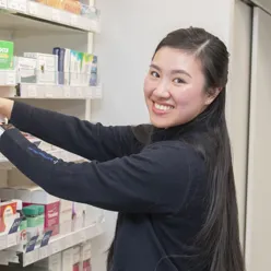 Thiet rydder i hyllene mens hun ser på kamera og smiler