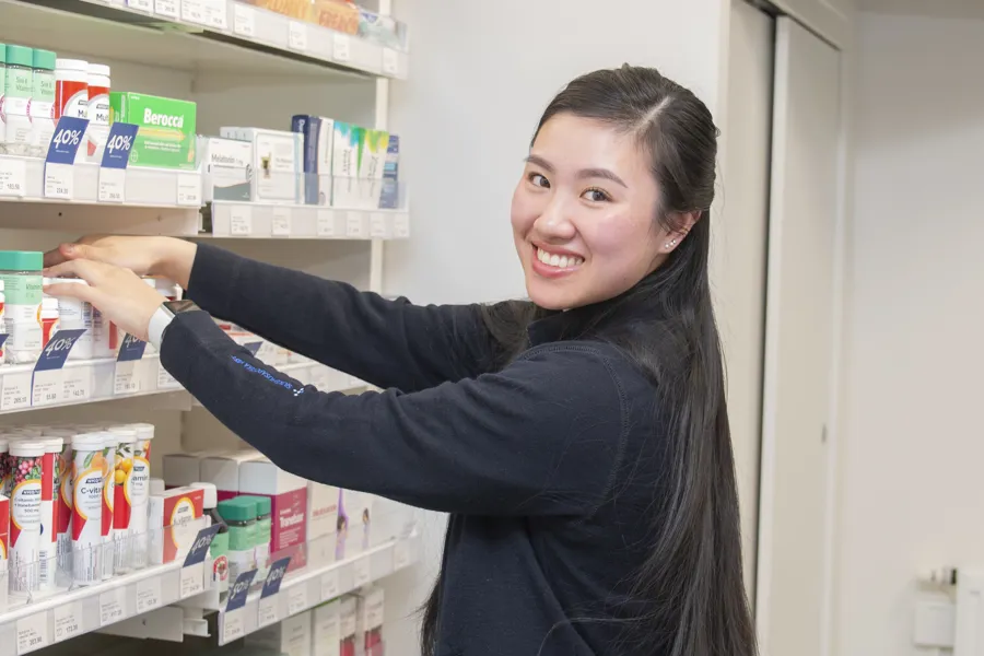 Thiet rydder i hyllene mens hun ser på kamera og smiler