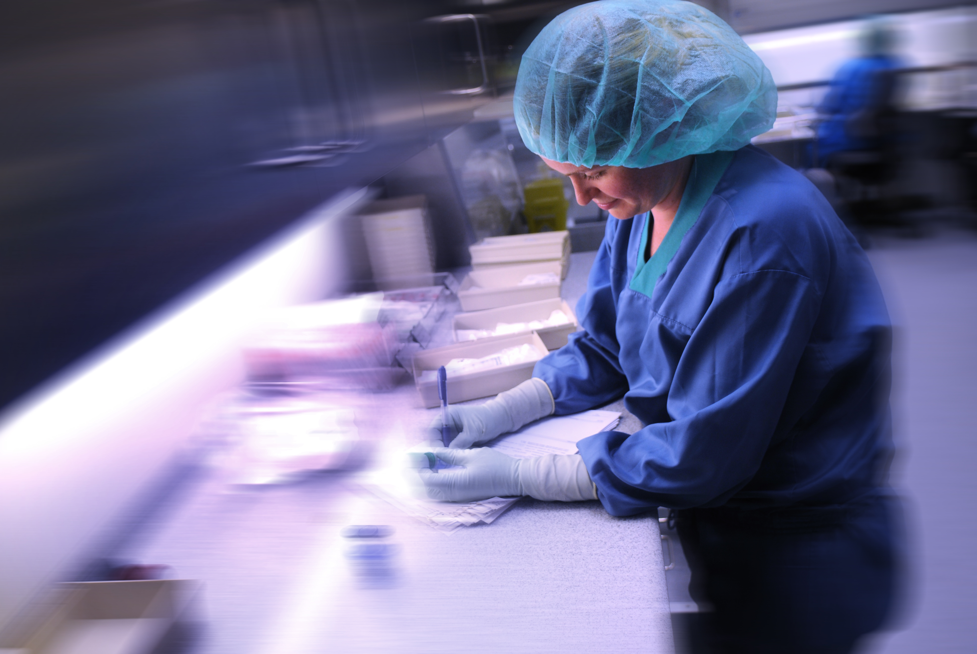 En kvinnelig apotektekniker produserer legemidler i produksjonsantrekk