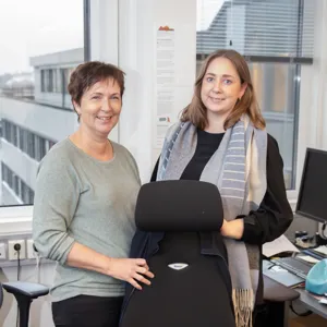 To damer i HR-avdelingen står ved siden av en tom kontorstol.