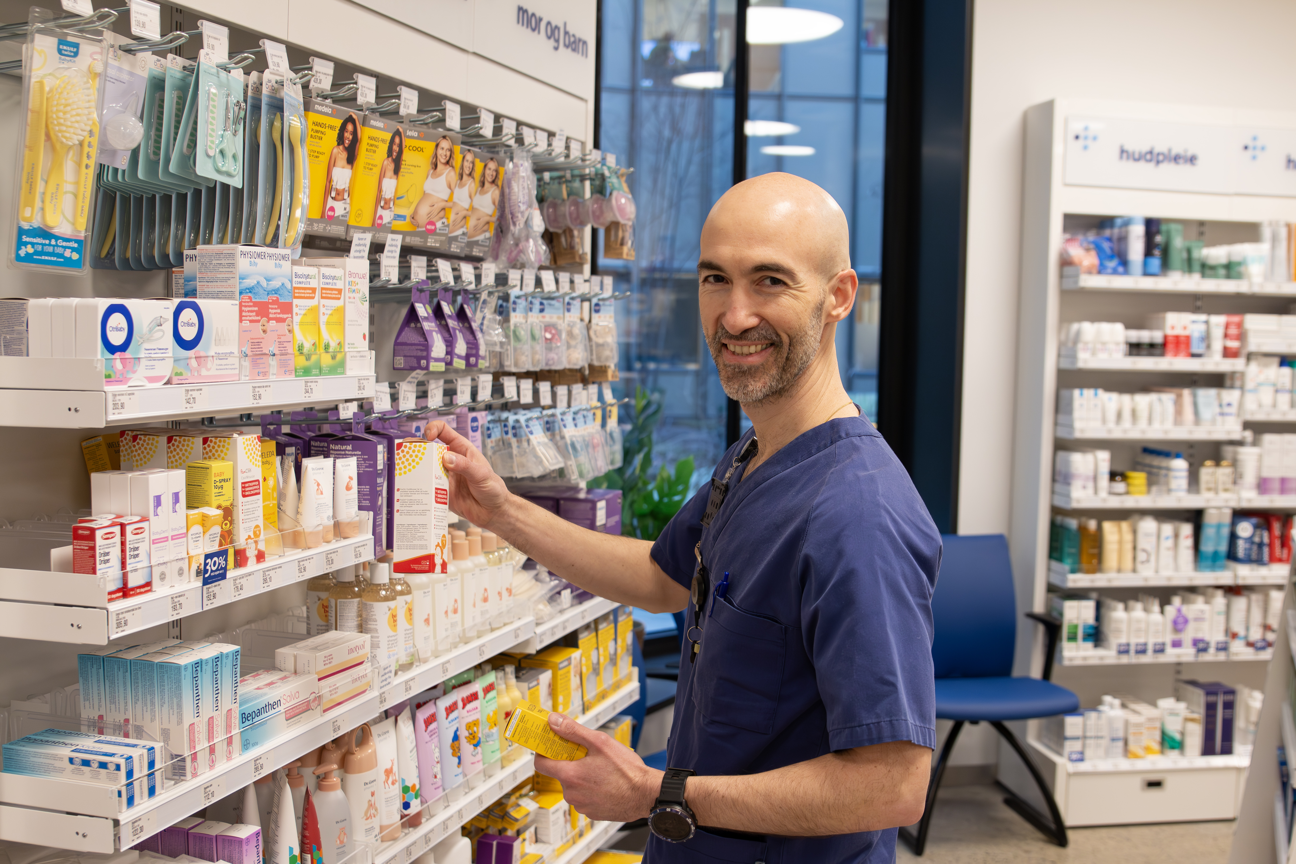 Ansatt i sjukehusapoteket står foran en hylle i apoteket