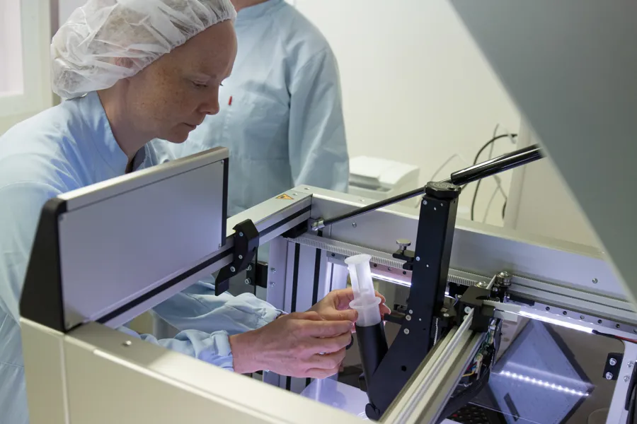 Ragnhild Haugse lener seg over 3d-printeren for å montere sprøyten som inneholder geleen med virkestoffet.