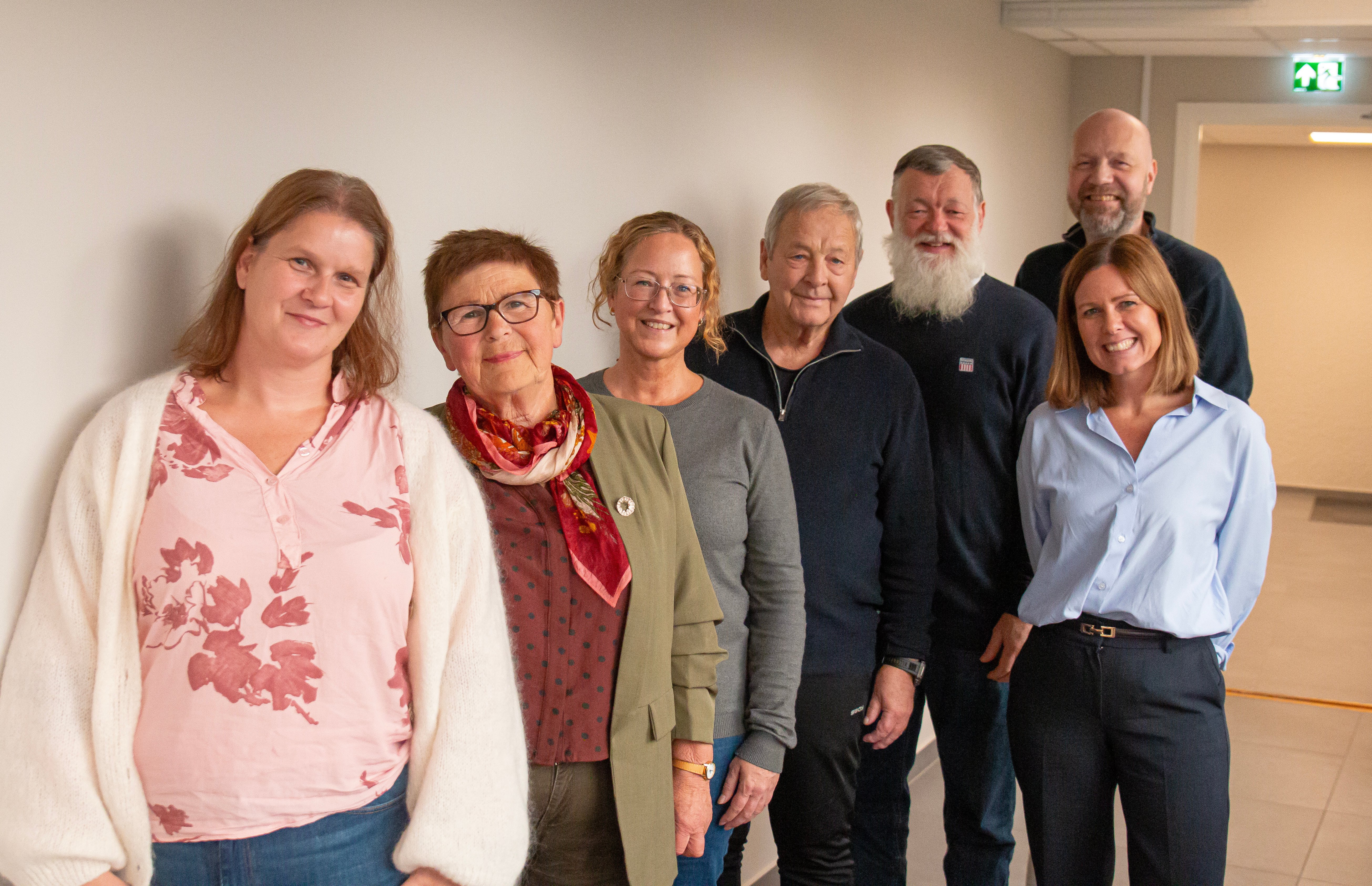 Brukerutvalget, som består av seks representanter står langs en hvit vegg. Administrerende direktør, Tonje Folkvang står ved siden av den bakerste.