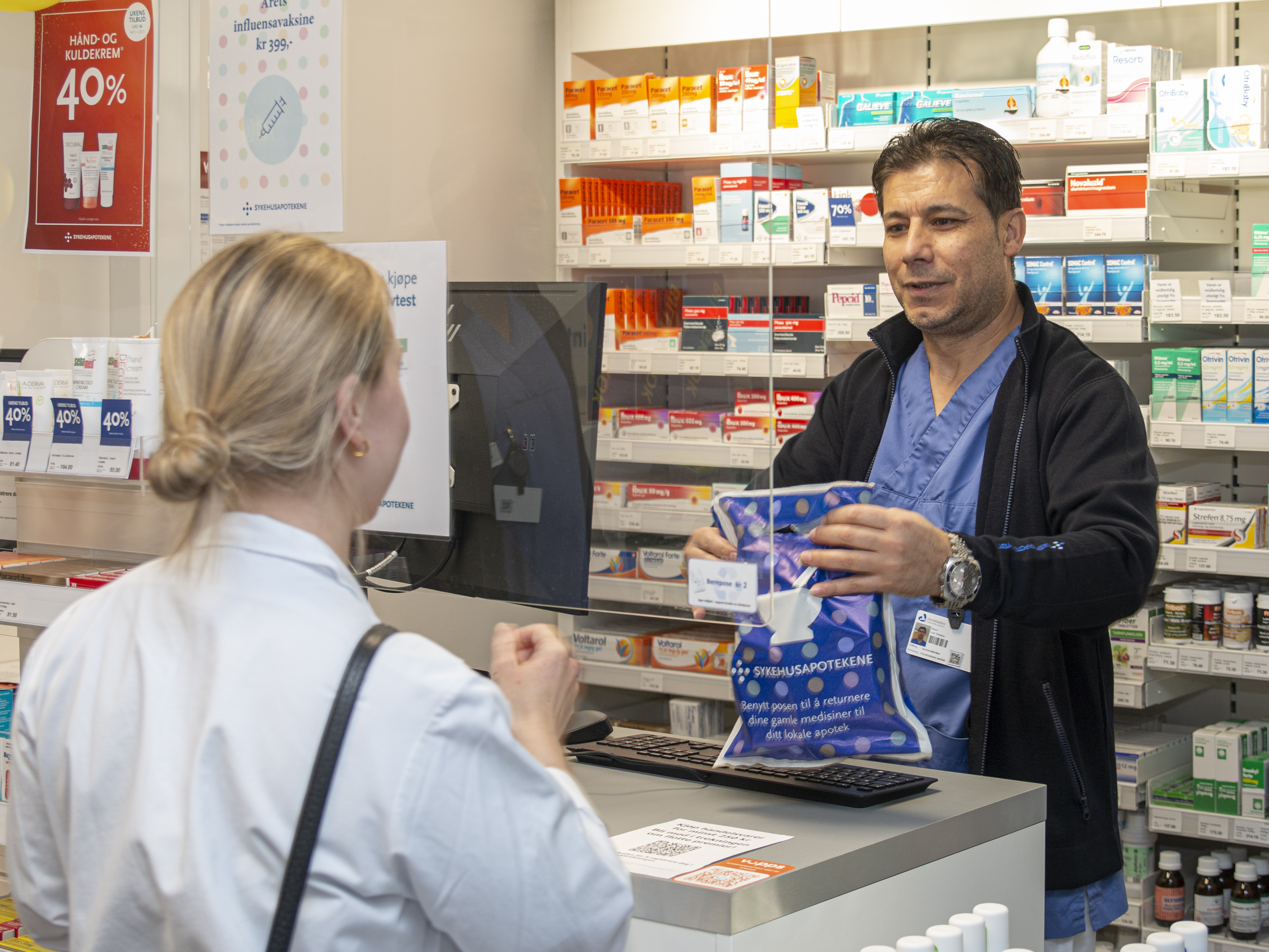 Ivar Hessou ekspederer en kunde ved sykehusapoteket på Haraldsplass. Han gir kunden posen med varene oppi.