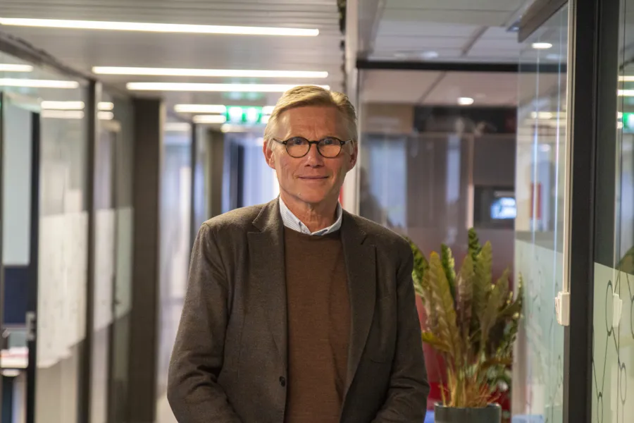 Helge Torgersen står og ser mot kamera. Han er kledd i dress og skjorte.