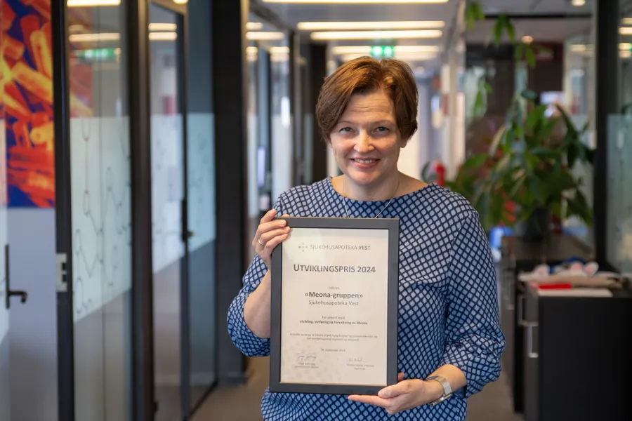 Kristin Slettvåg holder oppe prisen som hun har fått på vegne av Meona-teamet i Sjukehusapoteka Vest.